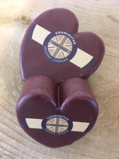 A picture showing two Godminster Heart cheeses on a wooden board