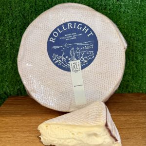 A picture showing a wheel of Rollright cheese with a cut wedge next to it. They are positioned on a wooden board with a green backdrop
