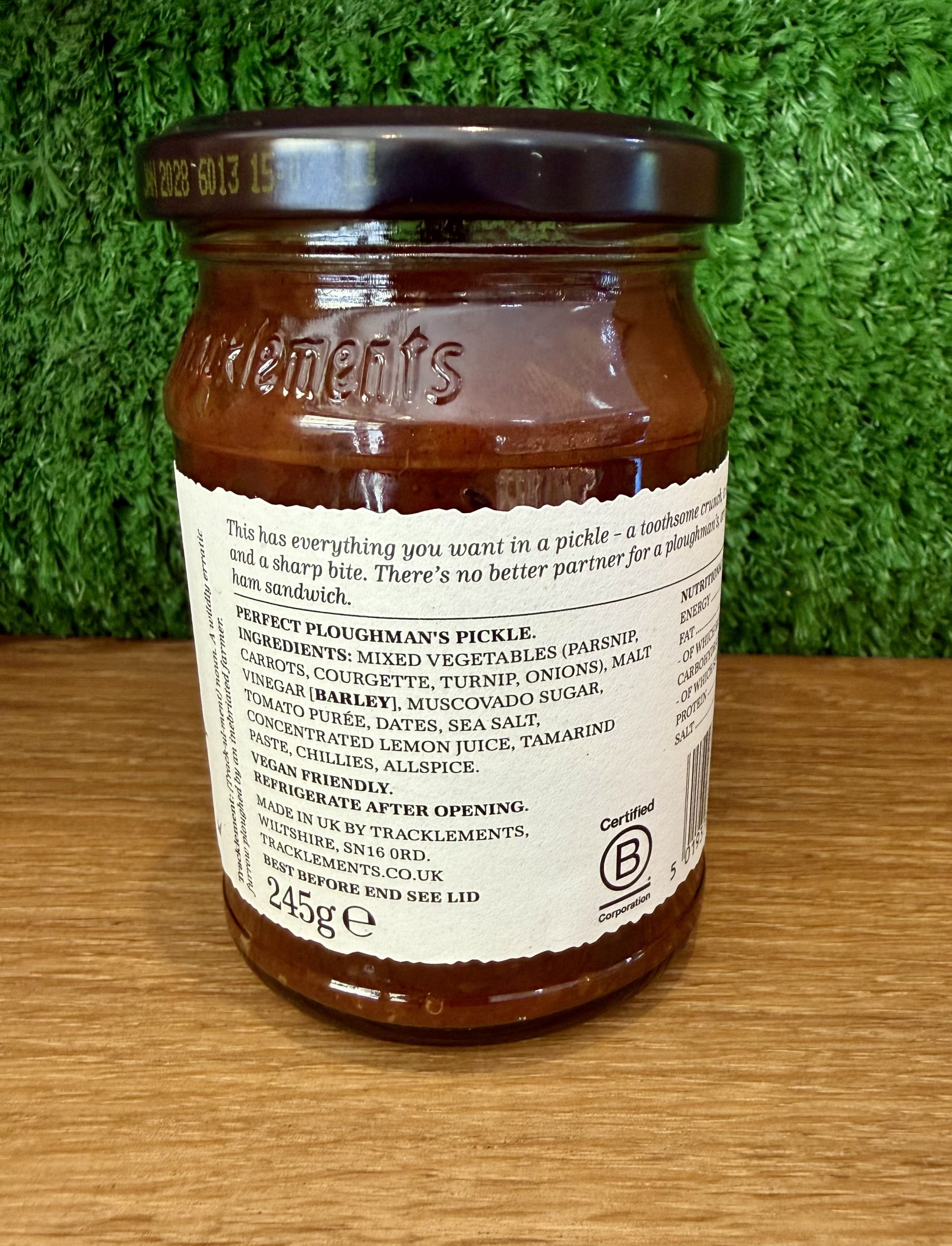 A photo of the back of a jar of Perfect Ploughman's Pickle. It is pictured on a wooden board with a green background