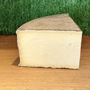 A picture of a chunk of gorwydd caerphilly. It is on a wooden board with a green background