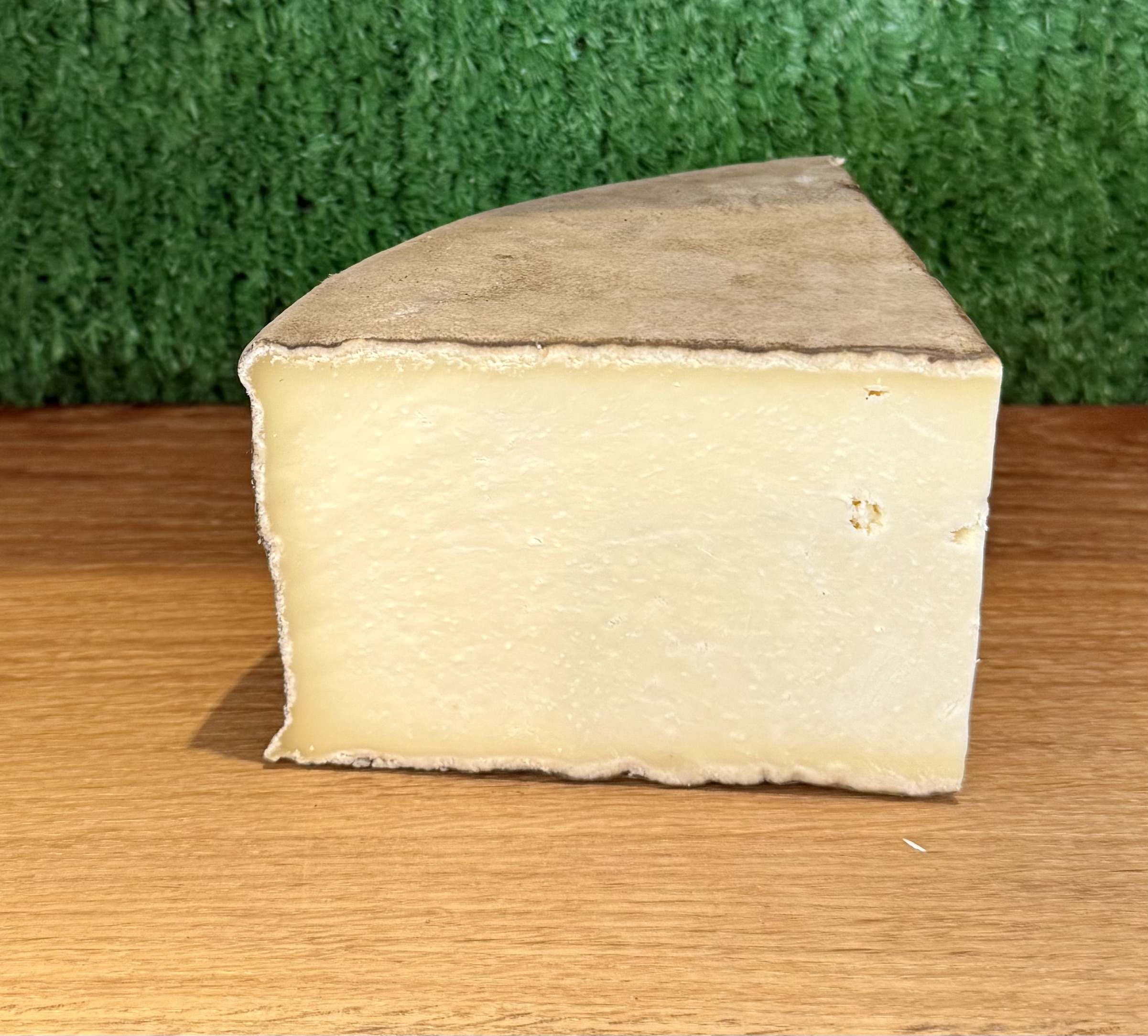 A picture of a chunk of gorwydd caerphilly. It is on a wooden board with a green background