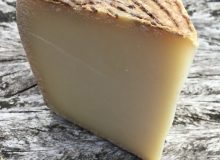 A picture of a wedge of Sardinian Pecorino (or Giuncato to give it its Italian name!) It has been placed on a rustic looking wooden table