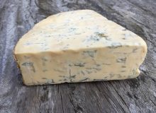 A picture showing a wedge of Beauvale cheese, placed on a wooden table