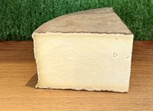 A picture of a chunk of gorwydd caerphilly. It is on a wooden board with a green background