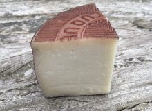 A photo depicting a wedge of Murcia al Vino PDO. It is pictured on a rustic looking wooden table.