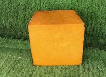 A picture of a block of Smoked Saxon Cross Cheddar. It is on a wooden board with a green background