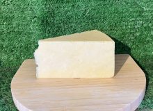 A picture showing a wedge of White Stilton PDO sat on a wooden board
